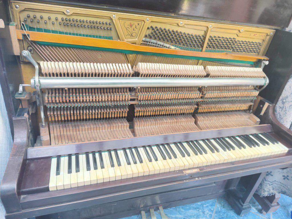 Piano vertical abierto para afinación, con el teclado, los martillos y las cuerdas a la vista